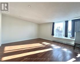 A room with wooden flooring and a window with curtains.