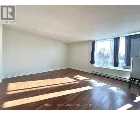A room with wooden flooring and a window with curtains.