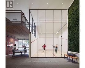 A man and a woman are playing squash in a room with a green wall on the side.