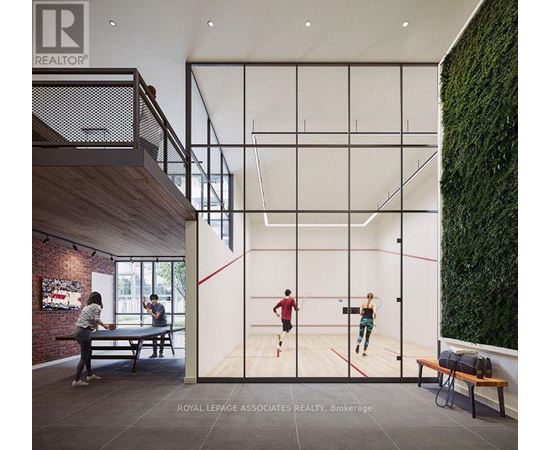 A man and a woman are playing squash in a room with a green wall on the side.