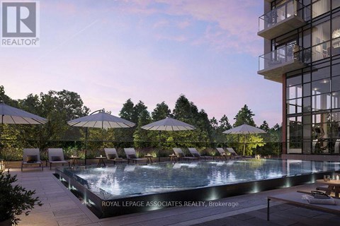A pool surrounded by lounge chairs and umbrellas in front of a building.