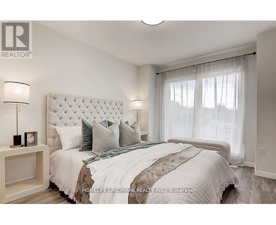 A bedroom with a large bed and a nightstand with a lamp.