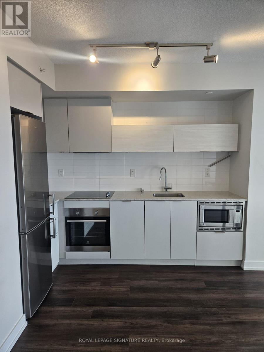 A kitchen with white cabinets and a stainless steel refrigerator.
