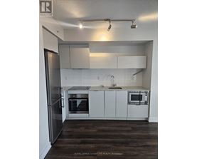 A kitchen with white cabinets and a stainless steel refrigerator.