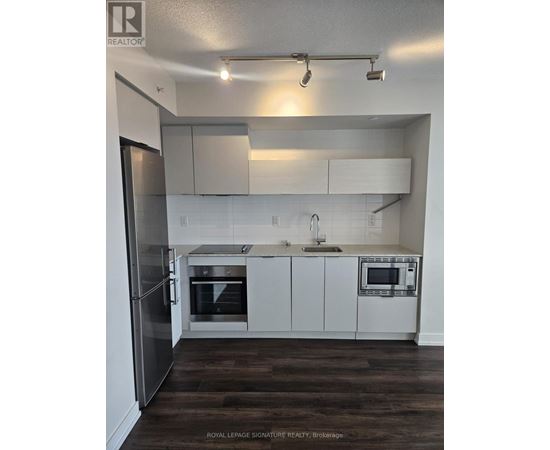 A kitchen with white cabinets and a stainless steel refrigerator.