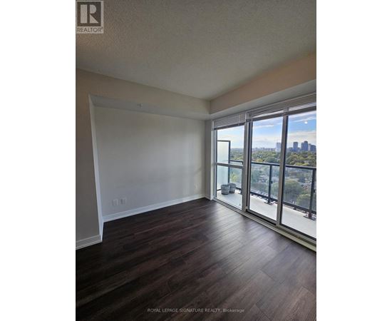 A room with wooden floors and a view of the city through the windows.