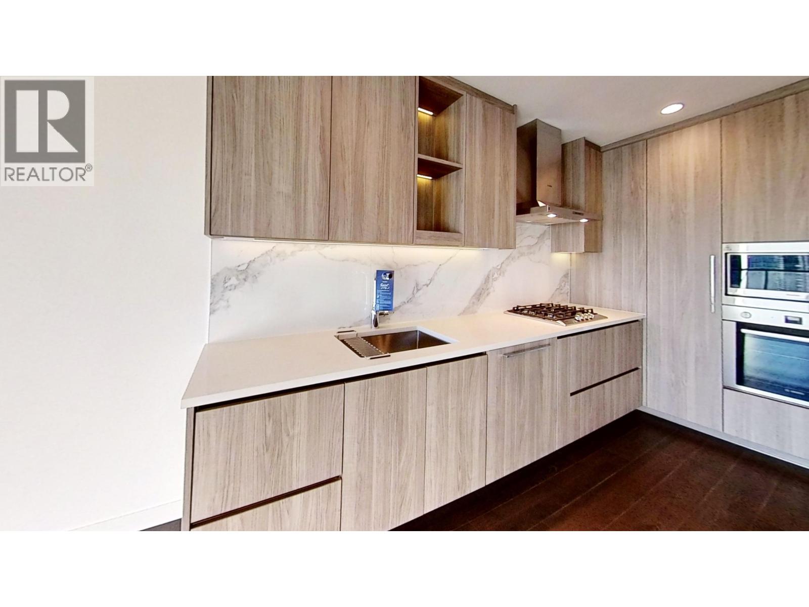 A modern kitchen with wooden cabinets and a marble countertop.