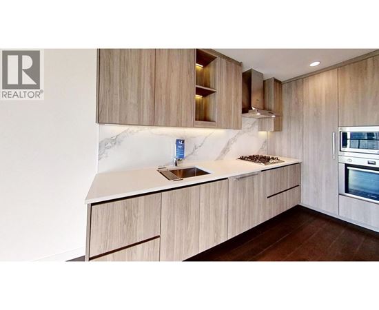 A modern kitchen with wooden cabinets and a marble countertop.
