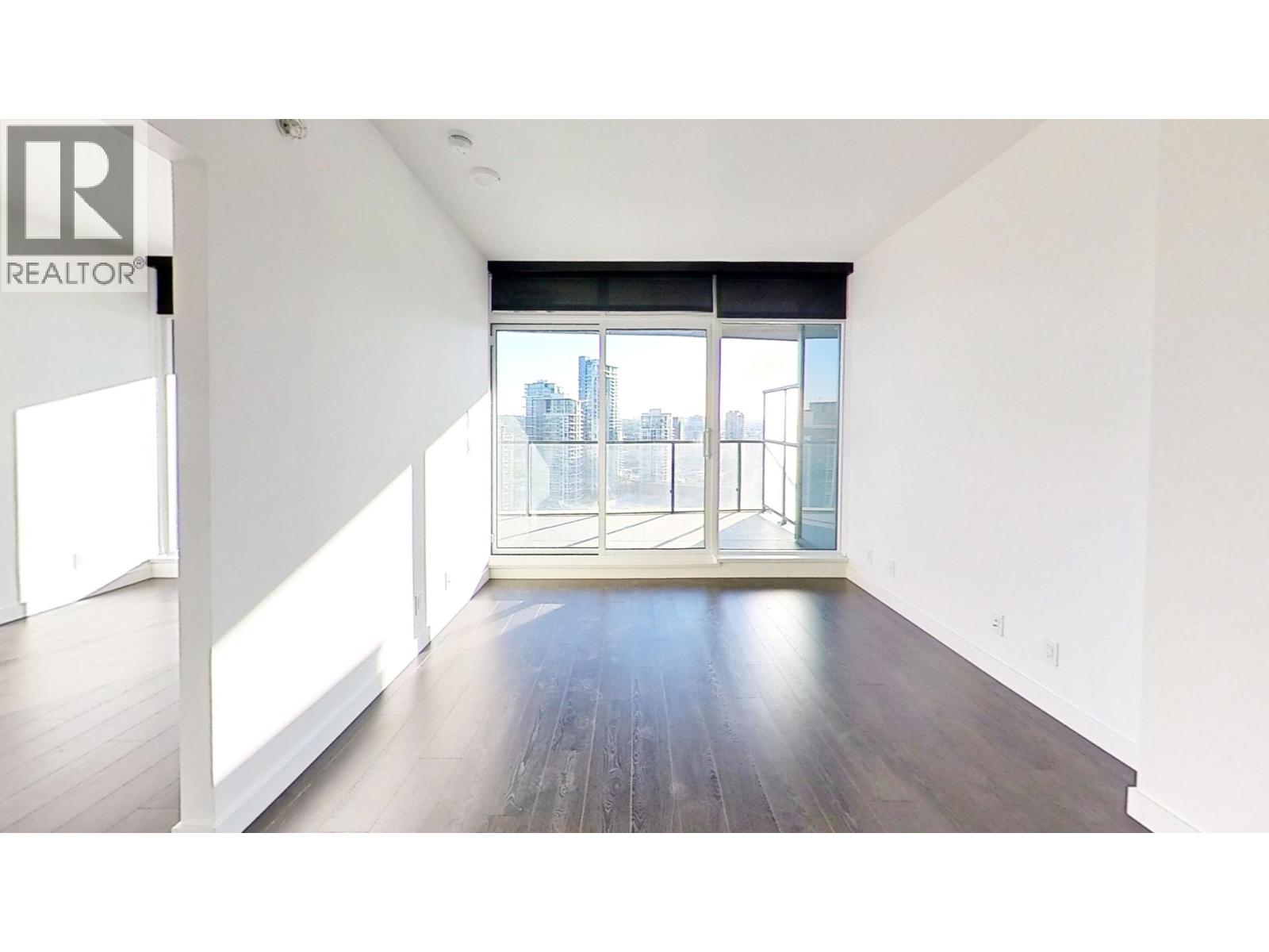 A large empty room with a view of the city through the windows.