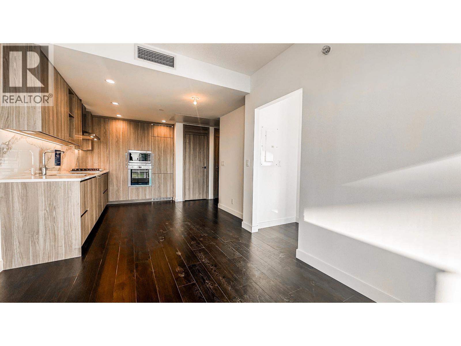 A modern kitchen with wooden floors and a white countertop.