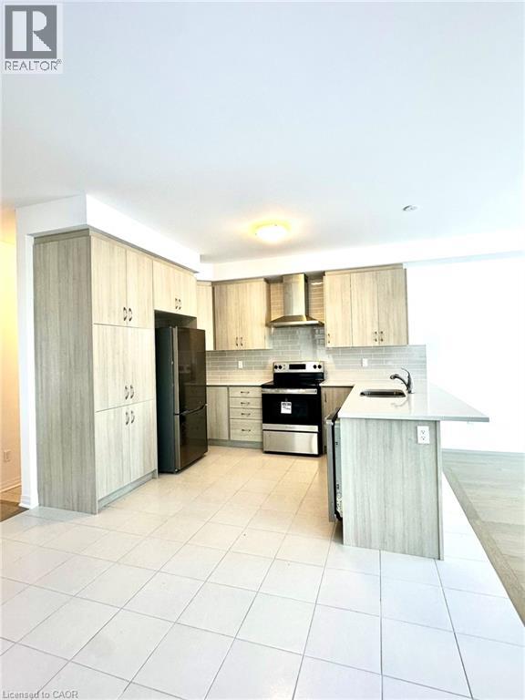 A modern kitchen with a black stove top oven and white tiled flooring.