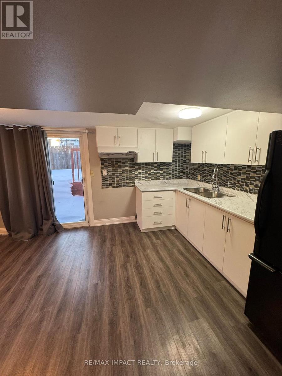 A kitchen with white cabinets and a black fridge.