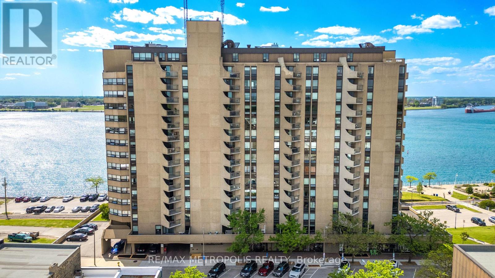 A tall residential building with a parking lot in front.