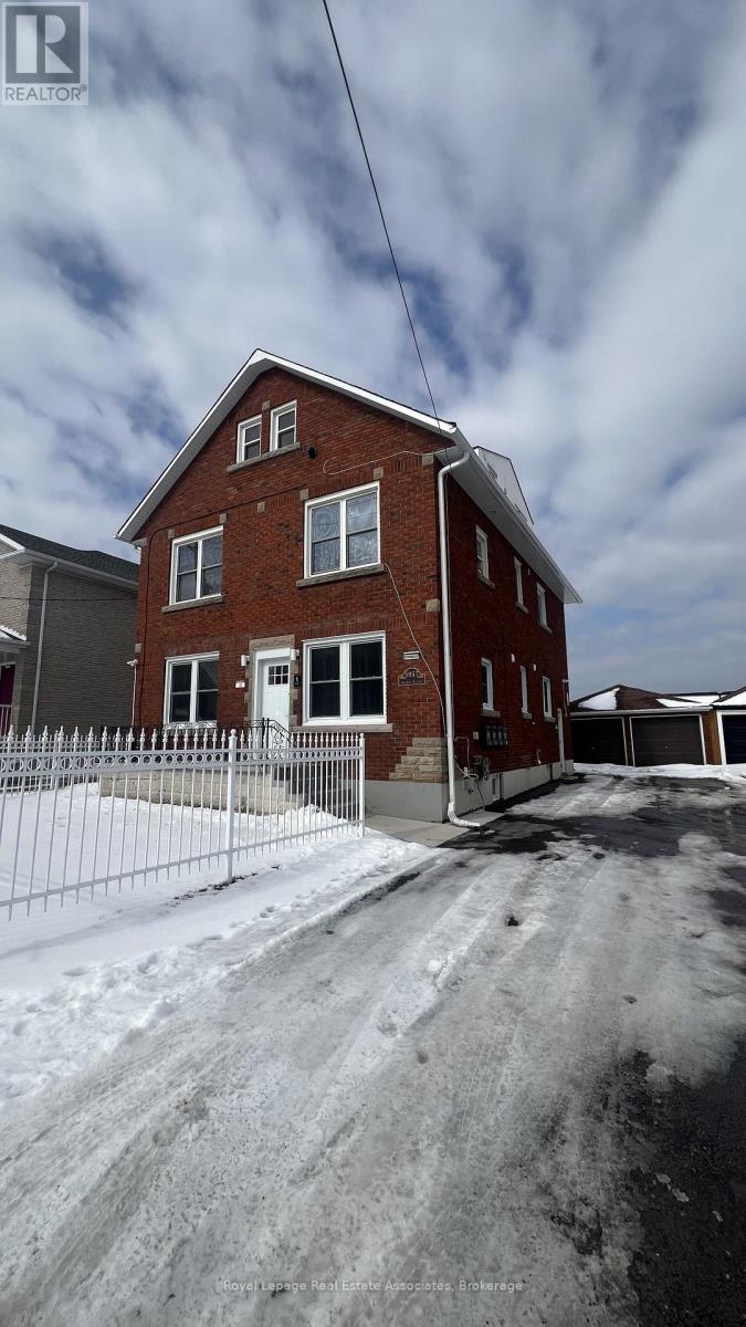 A red brick house with a white door and windows, surrounded by a snowy landscape.