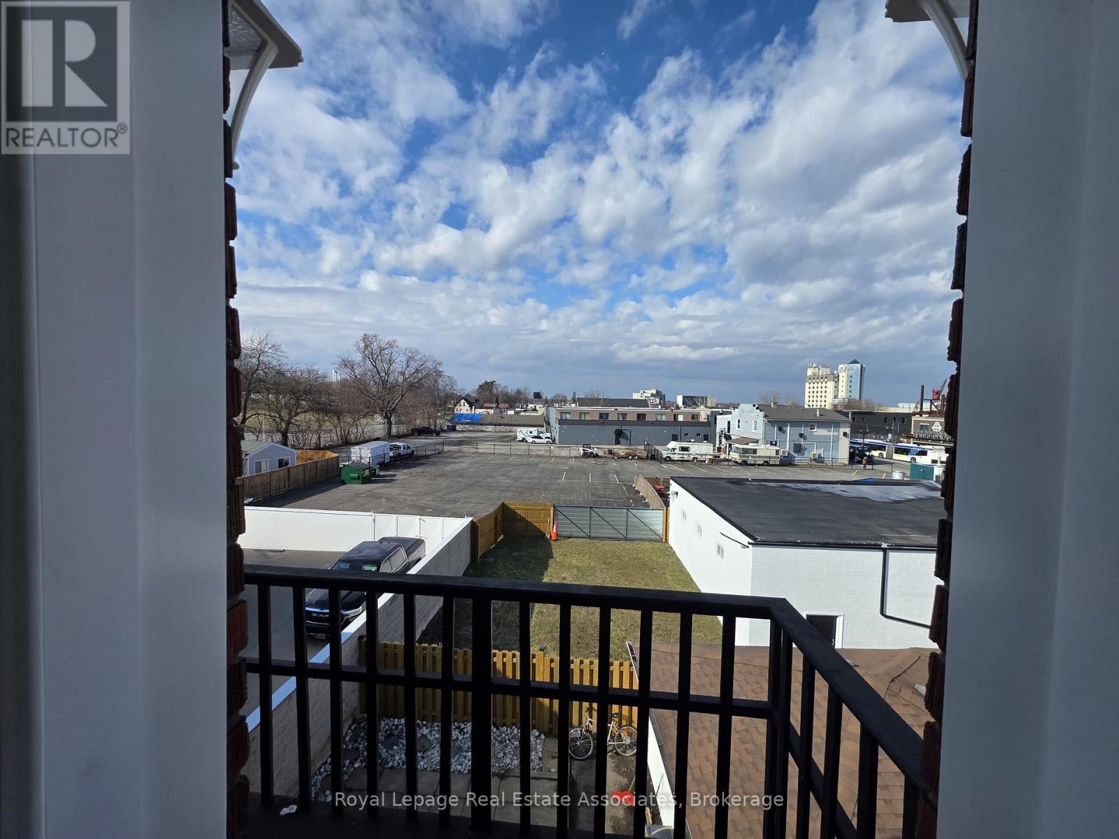 A view from a balcony looking out over a parking lot and buildings.