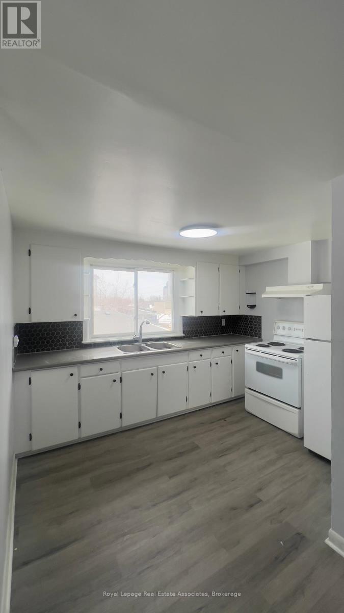 A kitchen with white cabinets and a wooden floor.