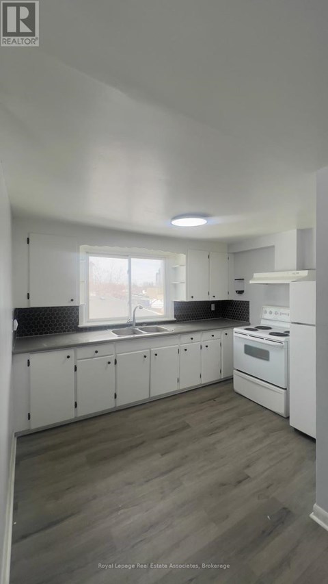 A kitchen with white cabinets and a wooden floor.