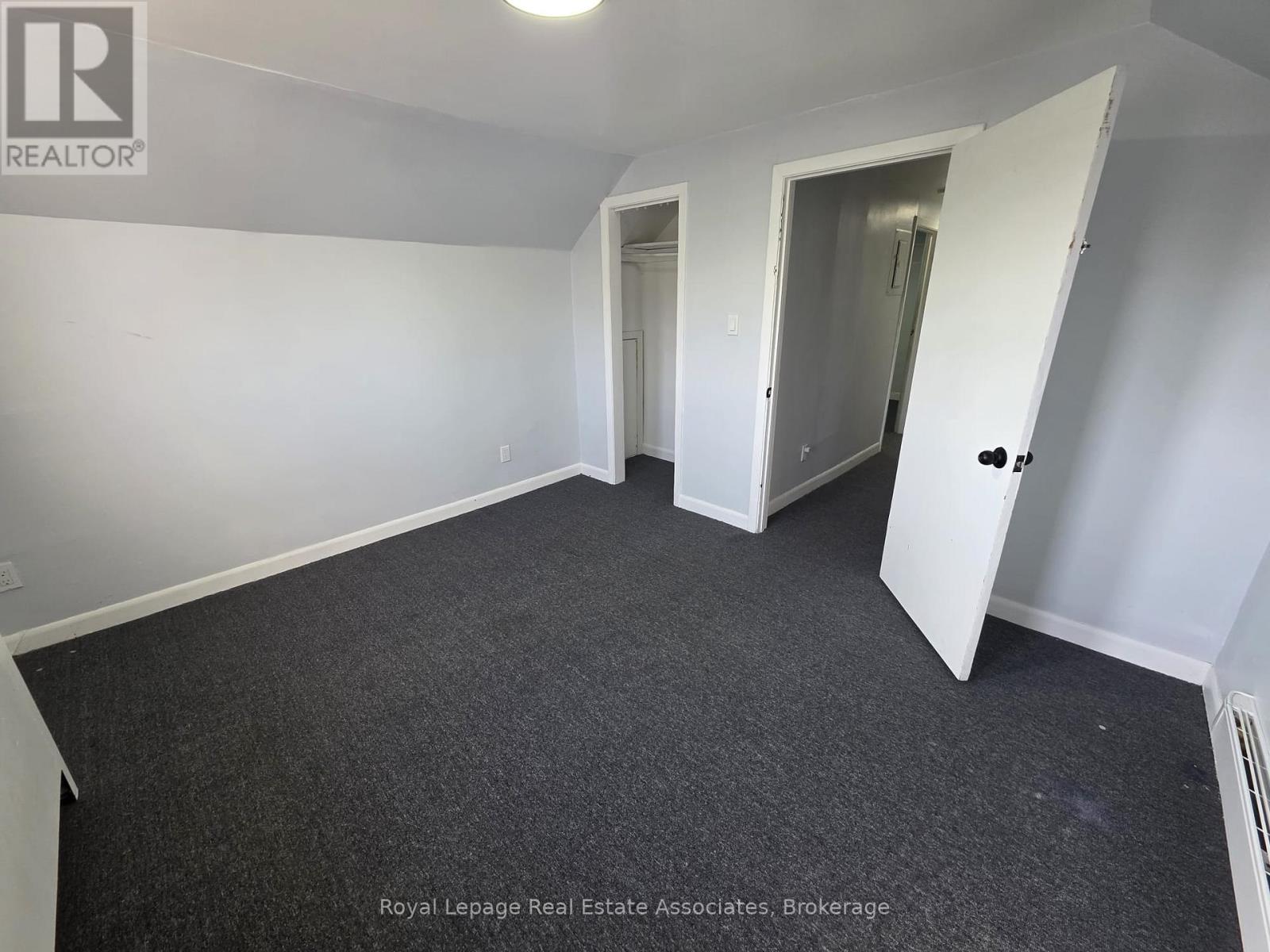A spacious room with a carpeted floor and white walls.