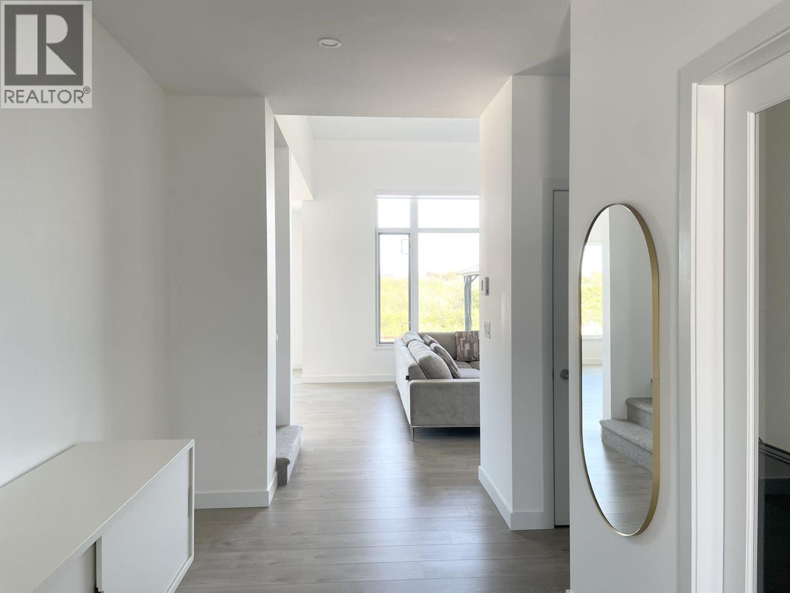 A modern living room with a grey sofa and a round mirror on the wall.