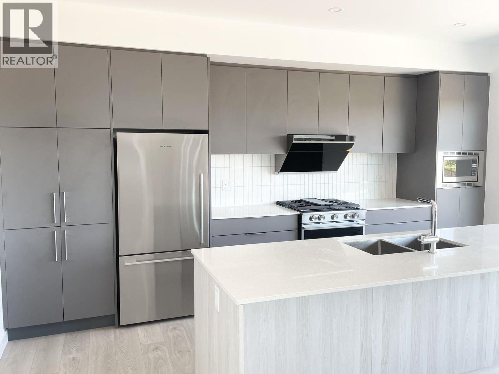 A modern kitchen with a white countertop and stainless steel appliances.