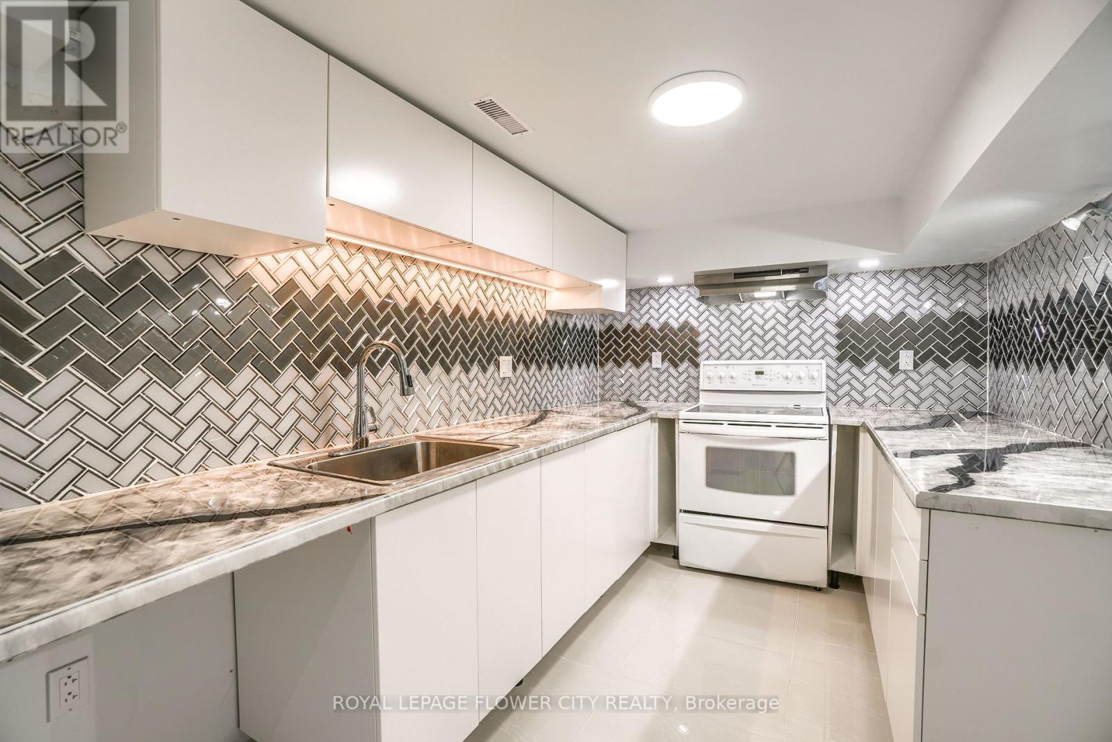 A modern kitchen with white cabinets and a black and white tiled backsplash.