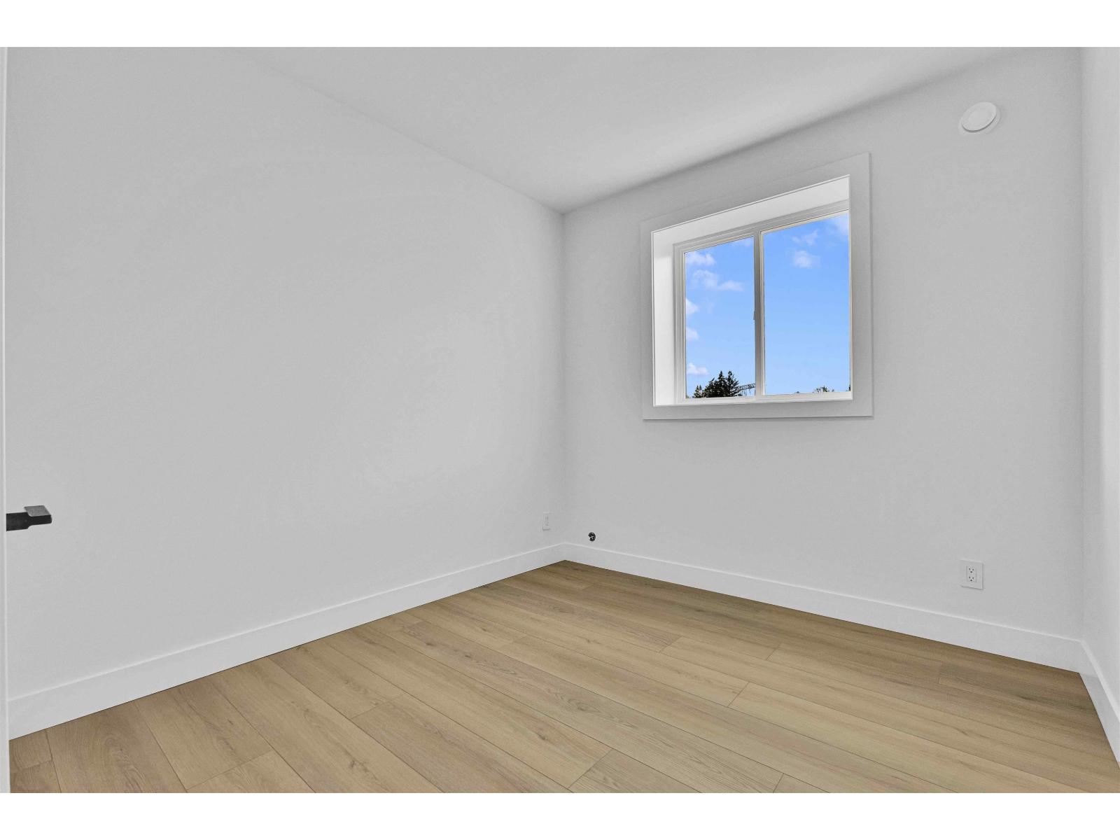 A room with a window and wooden flooring.