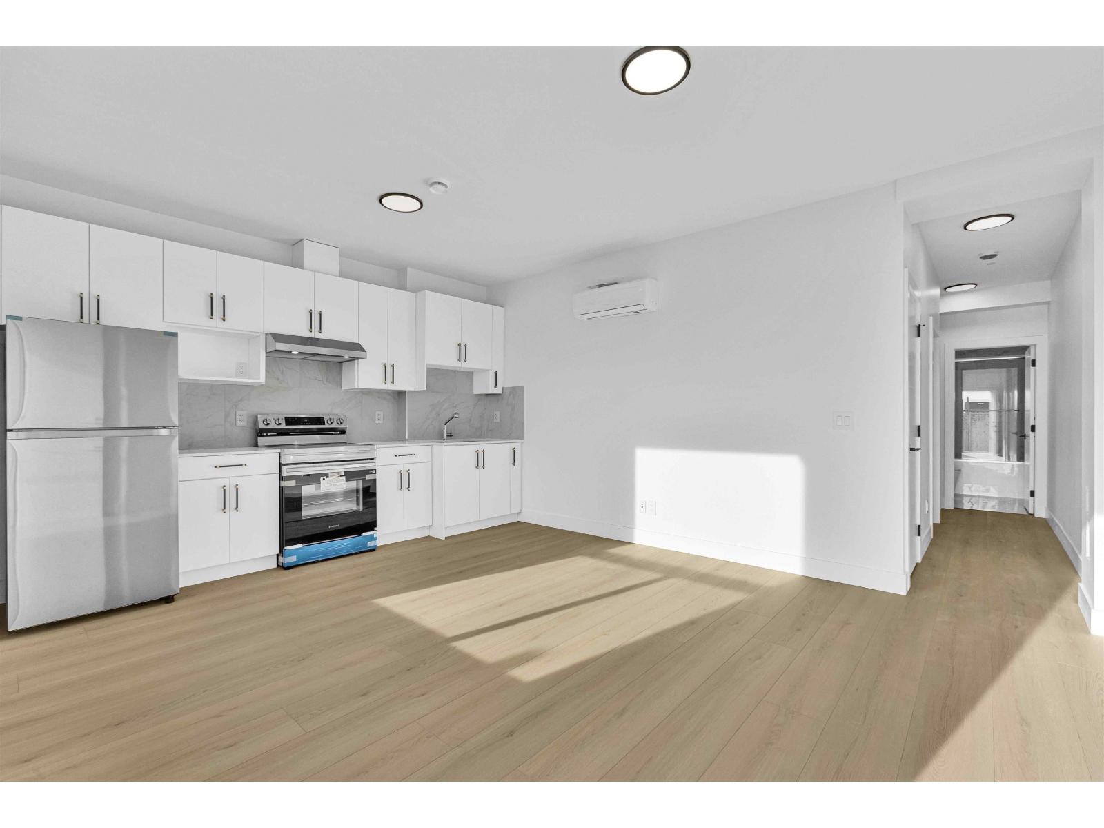 A modern kitchen with white cabinets and a wooden floor.