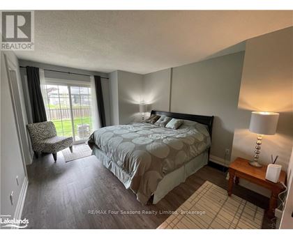 A bedroom with a large bed and a chair by the window.