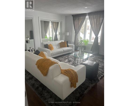 A living room with two white couches and a glass coffee table.