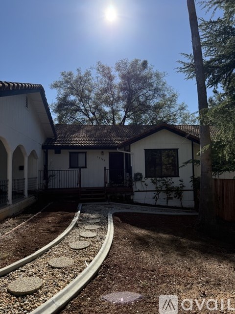 A house is surrounded by a fence and trees.