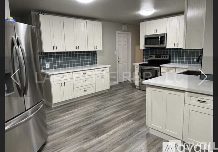 A kitchen with white cabinets and a stainless steel refrigerator.