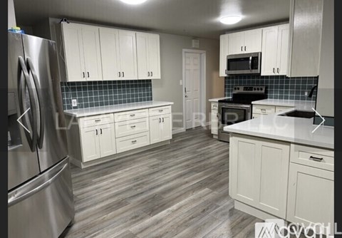 A kitchen with white cabinets and a stainless steel refrigerator.