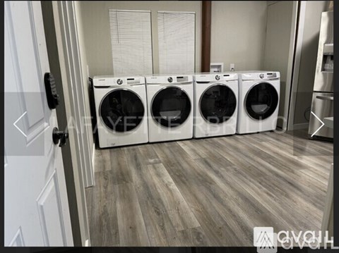 A row of white front load washing machines in a laundry room.