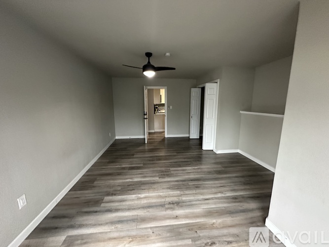 A spacious room with a ceiling fan and wooden flooring.