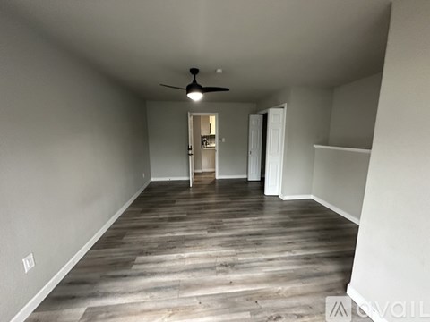 A spacious room with a ceiling fan and wooden flooring.