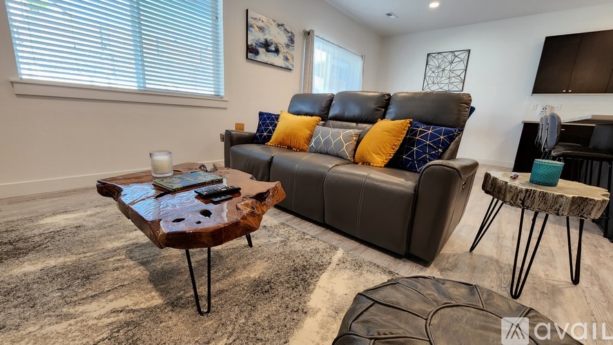 A living room with a brown leather sofa, a wooden coffee table, and a glass table.