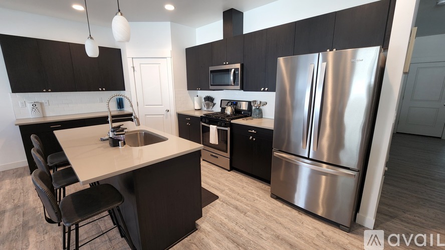 A modern kitchen with a stainless steel refrigerator and black cabinets.