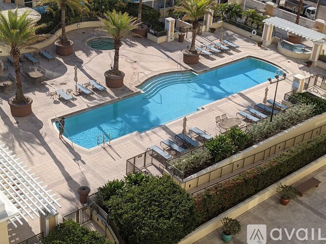 A large outdoor swimming pool surrounded by palm trees and lounge chairs.