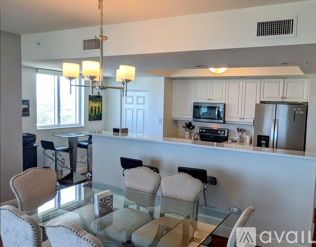 A kitchen with a glass table and chairs, a bar area, and a dining table.