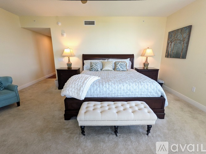 A bedroom with a large bed and a chair.