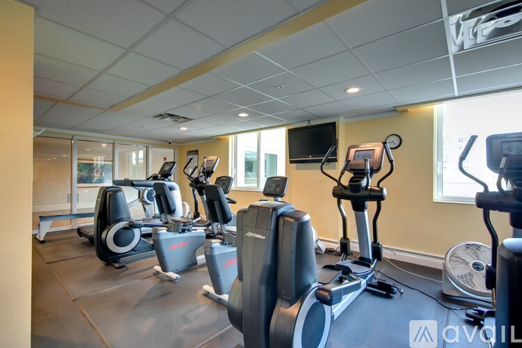 A gym with exercise equipment and a flat screen TV mounted on the wall.
