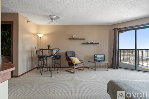 A living room with a sofa, a chair, a table, a television, and a balcony.