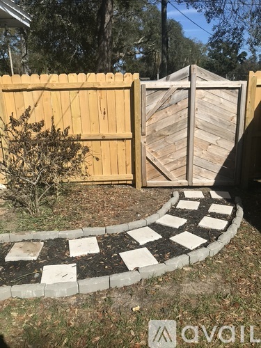 A wooden fence with a black and white checkered pathway in front of it.