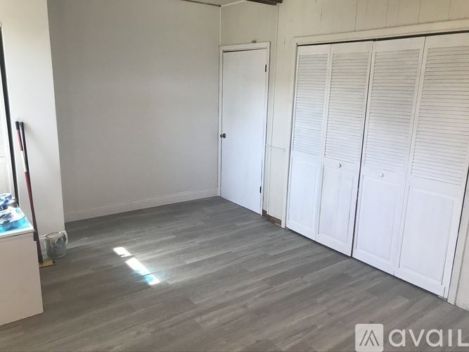 A room with a grey floor and white walls has a door and a cabinet.