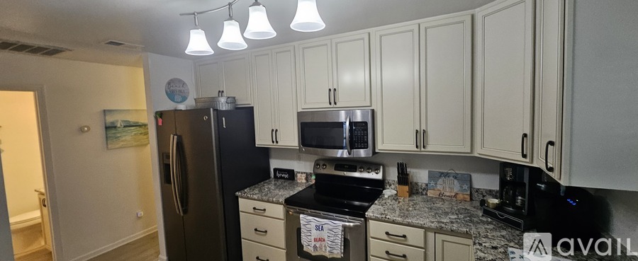 A kitchen with a black fridge and white cabinets.