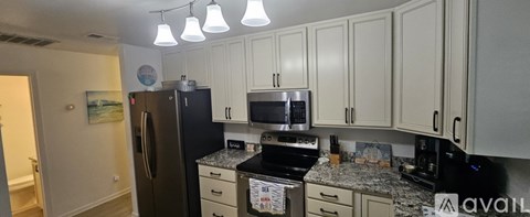 A kitchen with a black fridge and white cabinets.