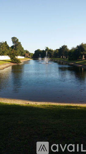 A fountain in the middle of a lake surrounded by grass.