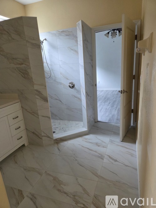 A bathroom with marble tiles and a walk-in shower.