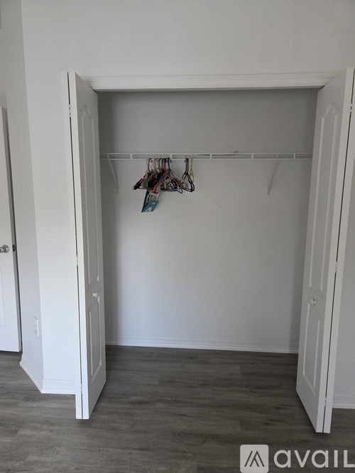 A white closet with a coat hanging on a rod.