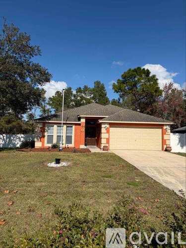 A house with a brown roof and a garage door is surrounded by trees.